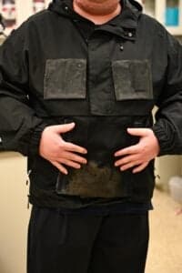 Researcher stands in a lab wearing a black jacket with a water-collecting textile in the front pocket.