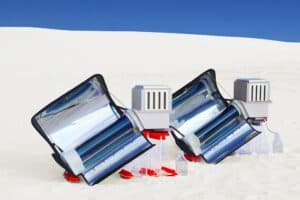 A device with solar panels sits in white-colored sand in the Chihuahuan Desert with a blue sky in the background.