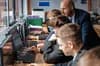 High school teacher overseeing students working at desktop computers in a classroom.