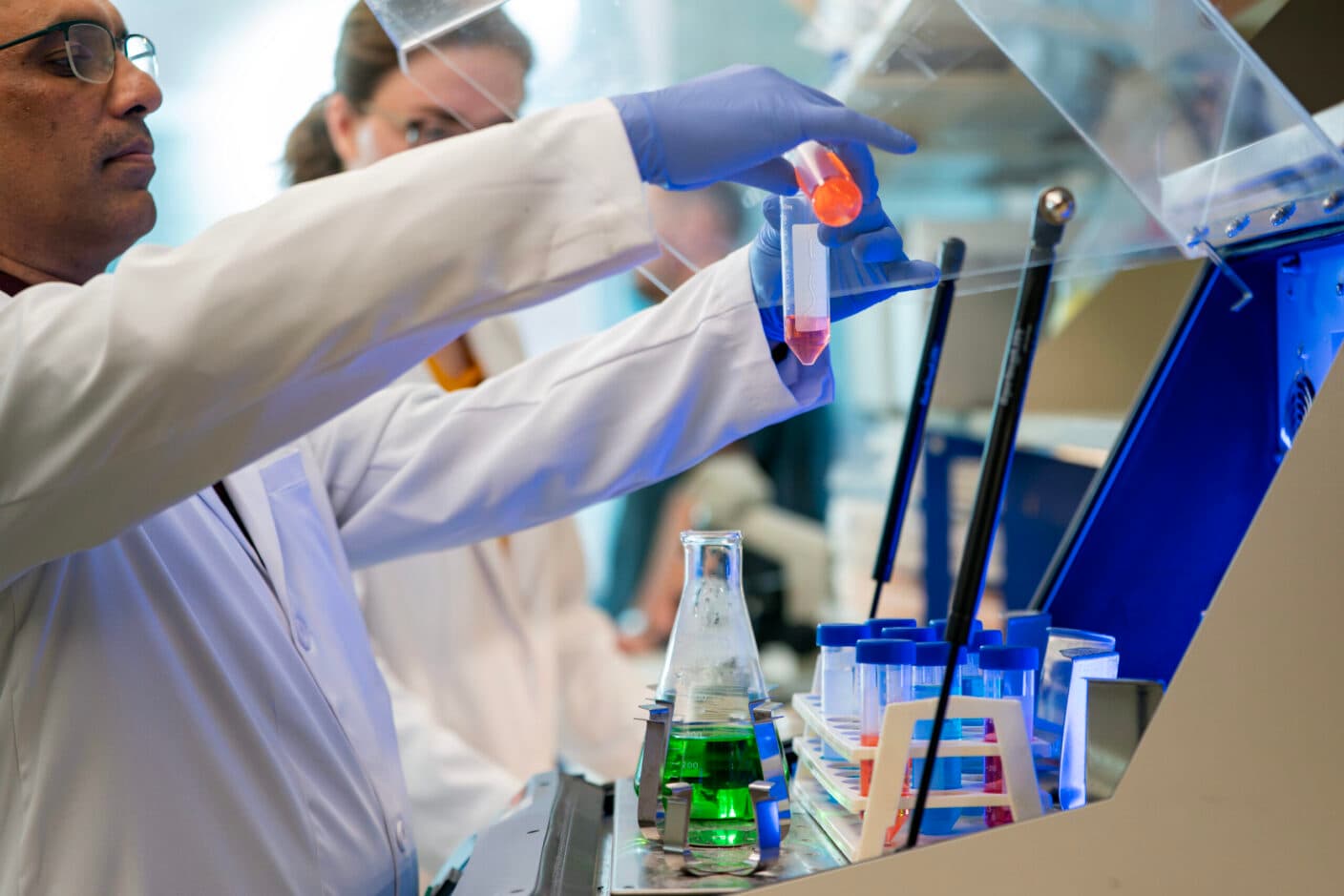 Scenes from the Shetty lab, with two students mixing two solutions into a centrifuge.