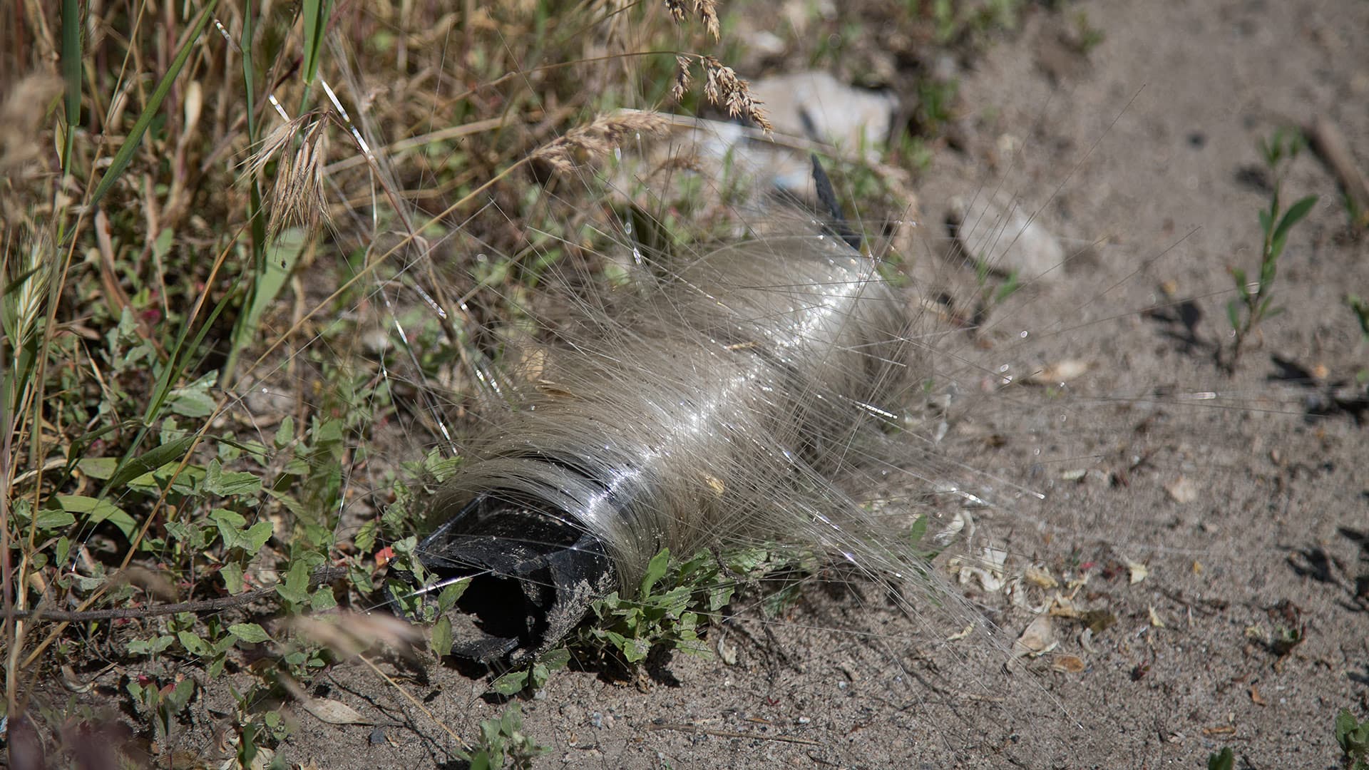 A spool of fiber-optic cable from a Russian FPV drone lies near a struck Ukrainian ground robotic system (UGV) armed with a machine gun on the streets of Druzhkivka