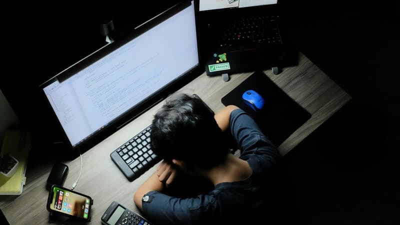 tired programmer sitting in front of computer with head put on the table