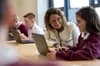 Lila Ibrahim and a young female student in a classroom, looking at a laptop while reviewing the student’s creative writing assignment.